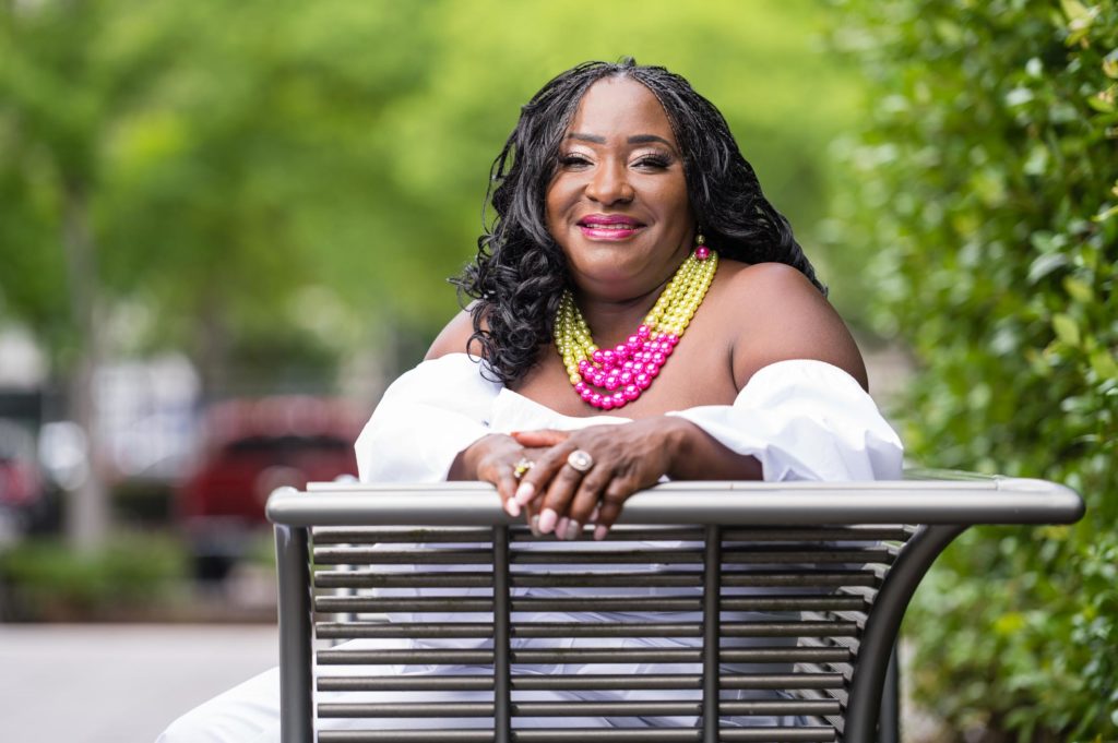 Woman posing on bench with jewelry (beads and ring) on while smile in Columbia South Carolina