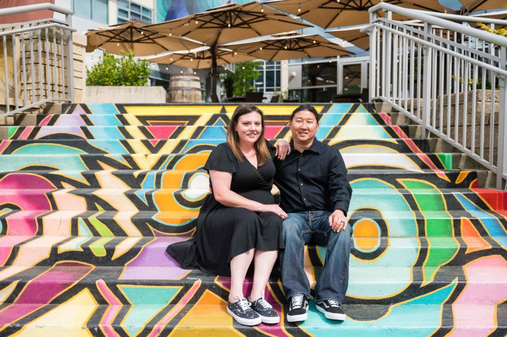 Couple hugging while sitting on multiple colors steps on uptown Charlotte North Carolina's Greenway.